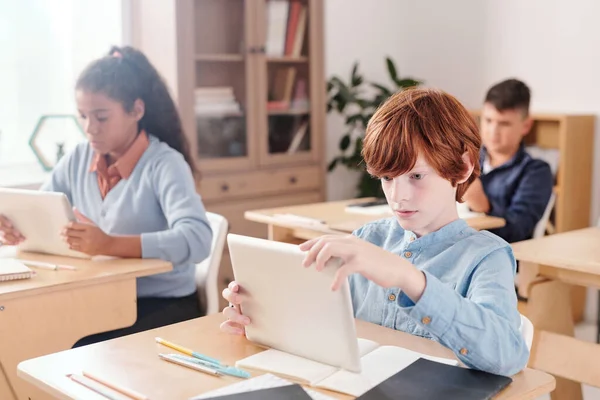 Seriös Skolpojke Med Pekplatta Tittar Igenom Online Dokument Medan Sitter — Stockfoto