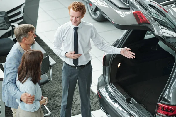 自信的年轻销售经理 穿着正装 打着领带 给客户展示汽车行李箱 并介绍新车型的所有机会 — 图库照片