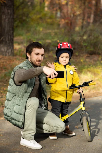 Akıllı Telefonlu Genç Baba Parkta Serinlerken Kasklı Bisikletinin Yanında Duran — Stok fotoğraf