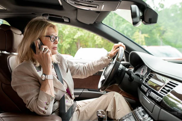 成功的优雅的女商人在开车 开车上班和打电话给客户或伴侣时通过掌舵 — 图库照片