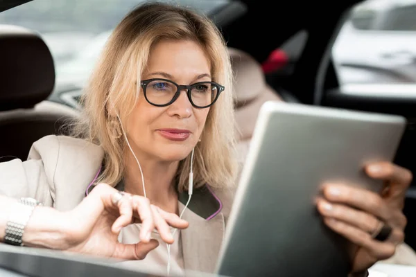Mature Blond Businesswoman Earphones Watching Online Video Tablet Display While — Stock Photo, Image