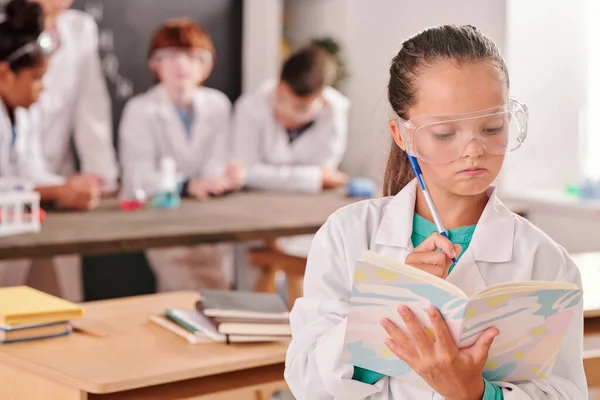 Pensive Schattig Schoolmeisje Whitecoat Bril Kijken Door Haar Notities Copybook — Stockfoto