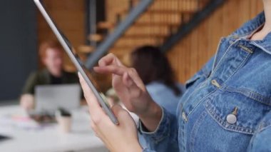 PAN, ofisinde tablet kullanan, kot ceketli, tanınmayan genç iş kadınının ellerini kapatıyor.