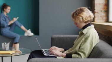 Yeni başlayan şirketlerin modern açık planlı ofisinde çalışan yaratıcı genç kadınların PAN çekimi.