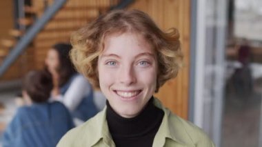 Kameraya gülümseyen genç iş kadını PAN 'ın portresi ve şirket kurma ofisinin toplantı odasında poz vermek. İş arkadaşları arka planda tartışıyorlar