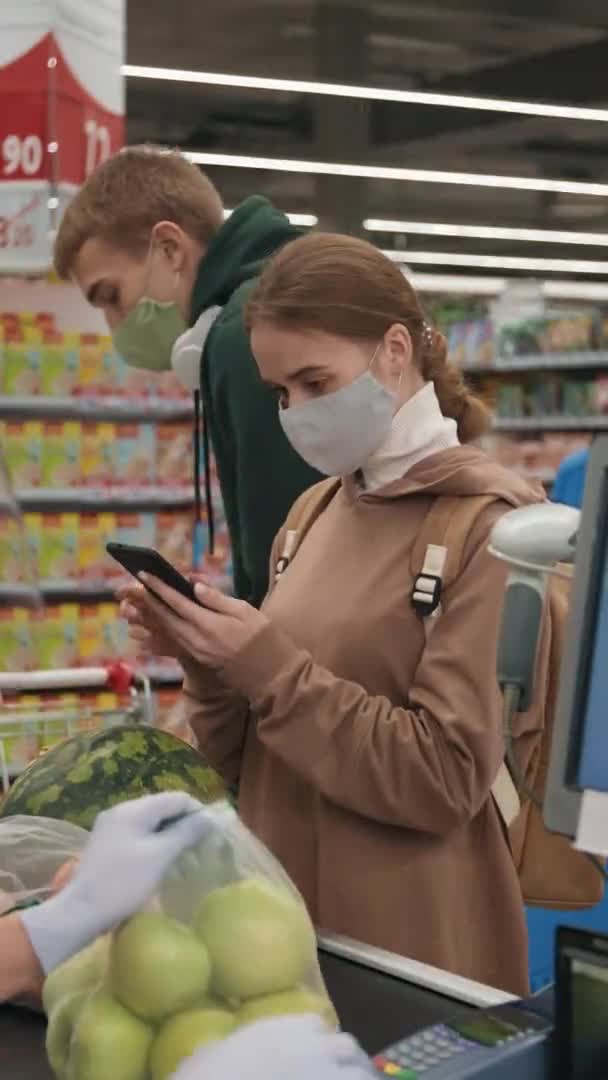 Maskeli Beyaz Bir Kızın Akıllı Telefondan Mesaj Atarken Kasiyer Gıda — Stok video