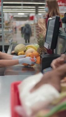 Orta bölüm ağır çekimde, tanınmayan siyah bir adam şık kıyafetler giymiş, nakit masasından taze meyve ve sebze alıyor ve onları alışveriş sepetine koyuyor.
