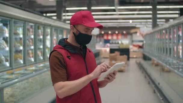 Kırmızı Şapkalı Yelekli Bir Erkek Tüccarın Hipermarketin Ortasında Ürünleri Saymak — Stok video