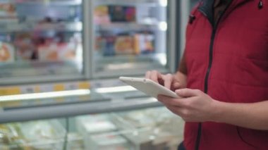 Orta bölüm yavaş çekim erkek hipermarket tüccarı tezgahlar boyunca yürür tablet notlar alarak
