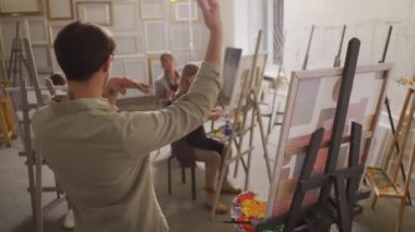 Profesyonel ressamın yüksek lisans sınıfına el kol hareketi öğretirken, bir grup öğrencinin soyut resmin temellerini açıklarken arka plan görüntüsü orta derece.