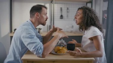 Evde kahvaltıda birbirlerini suçlayıp bağıran, kavgacı beyaz bir çiftin orta yavaş çekim görüntüleri.