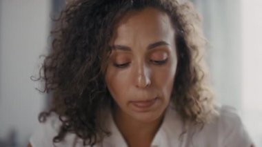 Kameraya küfreden, ilişki problemleriyle uğraşan, mutfak masasında oturduğunu kanıtlayan, rahatsız bir kadının yavaş çekim yakın çekimi.