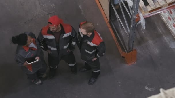 以上是三位身着工作服 站在库房里聊天 面带微笑地抬起头来对着摄像机的多民族劳动者的镜头 — 图库视频影像
