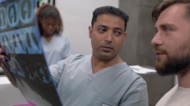 Arap erkek doktorun hastaya göğüs tomografisi çekerken ve teşhisi açıklarken orta boy görüntüsü.