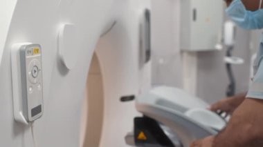 Yüz maskesi takan Arap erkek teknolojistin tomografi makinesini yavaş çekimleri.