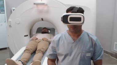 Hasta tomografisi sırasında görünmez arayüz kullanarak VR gözlüklü Arap erkek teknolojisinin orta boy görüntüsü.