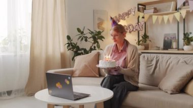 Kafkasyalı bir kadının bilgisayarda videoya çekilip güzel doğum günü pastasının üzerinde mumlar söndürdüğü ve tecrit sırasında evde yalnız kaldığı orta büyüklükte görüntüler.