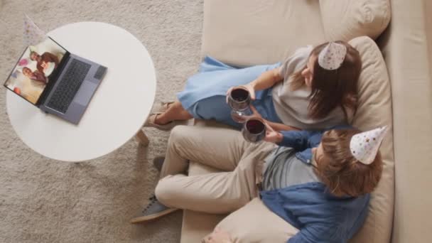 Şenlik Şapkalı Kırmızı Şarap Kadehleriyle Kanepede Oturan Mutlu Çiftin Doğum — Stok video