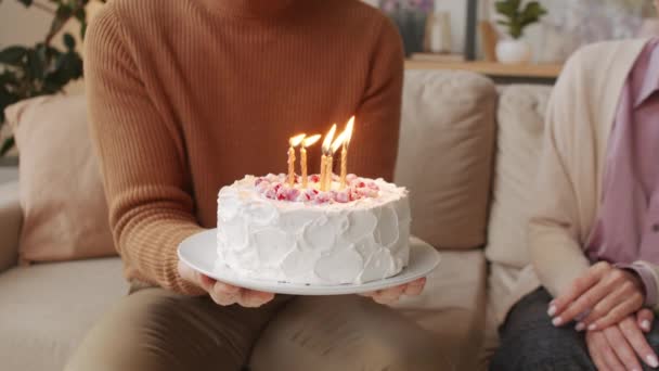 身着舒适毛衣的男人拿着漂亮的生日蛋糕 点着蜡烛 然后和坐在他旁边的女人一起把蛋糕吹灭 — 图库视频影像