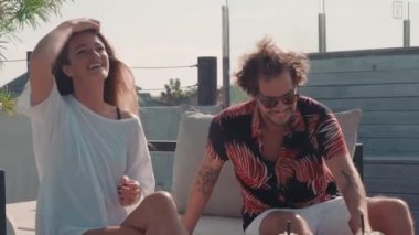 Yakışıklı bir adam kokteylleri yudumlarken ve eğlenirken neşeli ve güzel bir kadının yüksek sesle güldüğü orta boy bir fotoğraf.