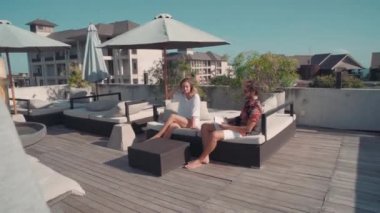 Garsonun havuz başında konuşan ve rahatlatan genç çifte kokteyl servis ederken çekilen fotoğrafı.