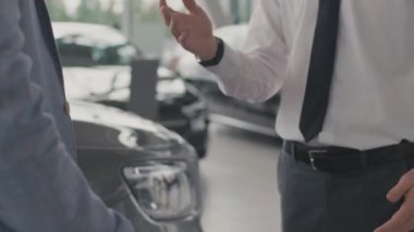Tanımlanamayan erkek müşteri ve satıcının resmi kıyafetlerle el sıkıştığı orta bölüm yakın çekim.