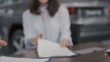 Tanımlanamayan adamın yavaş yavaş araba anlaşmasını kapatması ve satış temsilcisiyle el sıkışması.