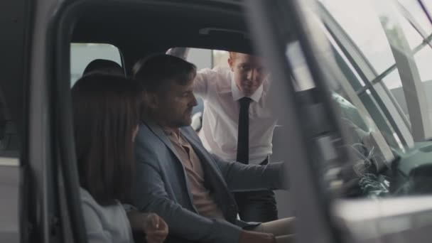 Tracking Shot Couple Sitting Car Dealership Talking Young Salesman — Stock Video