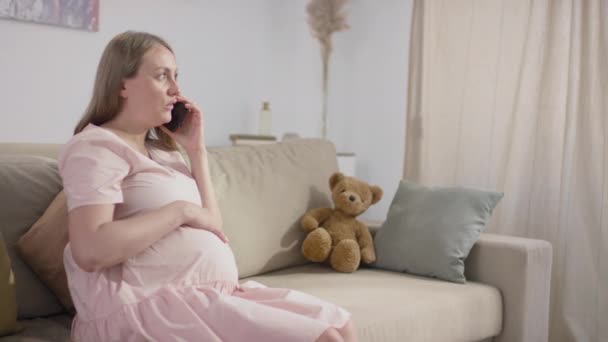 Kafkasyalı Hamile Bir Kadının Parlak Oturma Odasındaki Koltukta Oturup Telefonla — Stok video