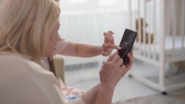 Hamile kadının omuz üstünden yakın plan fotoğrafı akıllı telefondan anneye bebeğin ultrason görüntüsünü gösteriyor. Gelecekteki bebek hakkında konuşuyorlar. Evde oturuyorlar.