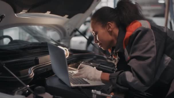 Handheld Shot Wesoły Czarny Kobieta Mechanik Samochodowy Rękawiczki Wpisując Laptopie — Wideo stockowe