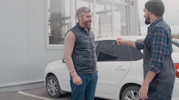 Ręczne Ujęcie Brodatego Mechanika Samochodowego Kombinezonach Rozmawiającego Klientem Zwracającego Kluczyki — Wideo stockowe