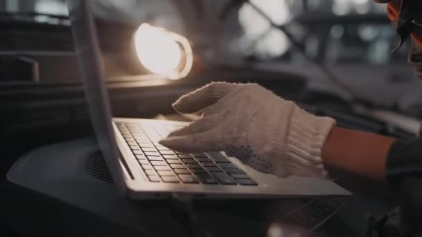 戴手套在手提电脑上输入无法辨认的女汽车技师的近照 放在敞篷下 — 图库视频影像