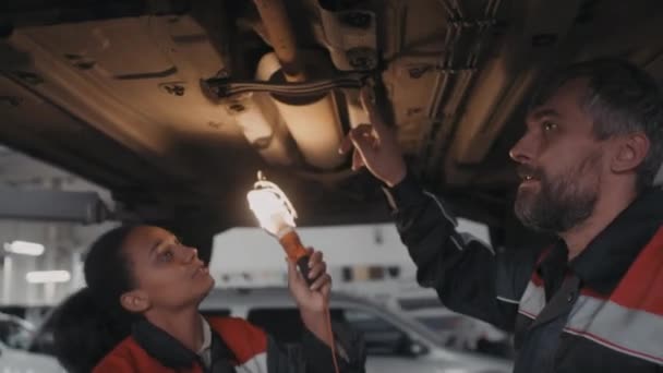 Ręczne Ujęcie Mechaniki Samochodowej Mężczyzn Kobiet Mundurach Kontrolujących Podwozie Samochodu — Wideo stockowe