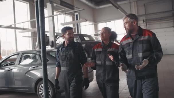 Slowmo Śledzenie Zespołu Mechaników Samochodowych Mundurach Rozmawiających Spacerujących Razem Garażu — Wideo stockowe