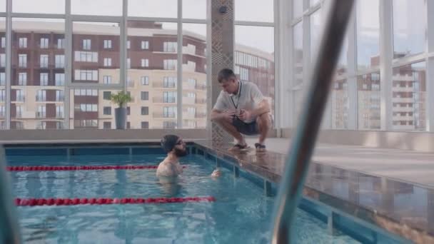 Visão Lateral Lentidão Treinador Masculino Com Cronômetro Agachado Piscina Conversando — Vídeo de Stock