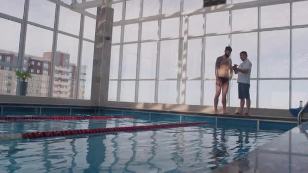 Szerokie Ujęcie Samca Pływaka Bez Koszuli Spodniach Rozmawiającego Trenerem Stoperem — Wideo stockowe