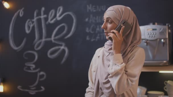 Średnie Zbliżenie Uśmiechniętej Muzułmanki Właścicielki Małej Stołówki Prowadzącej Rozmowę Telefoniczną — Wideo stockowe