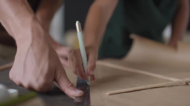 鉛筆と定規を使用して一緒に手作りの紙凧を作る認識できない男と男の子のミッドセクションスローモーションショットアウトラインを描くために — ストック動画