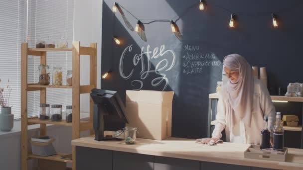 職場での女性イスラム教徒のコーヒーセラーの中出し現金机を掃除するための準備カフェを開くために取得 — ストック動画