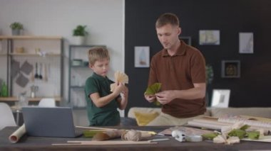 Orta ölçekli gülümseyen baba ve oğulun evde el yapımı uçan uçurtma kuyruğu için renkli papyonlar yaptığı fotoğraf.