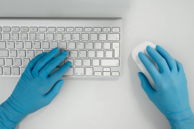 Çağdaş sağlık çalışanının eldivenli ellerine bir göz at. Bilgisayar faresine tıkla ve iş yerindeki tuşlara bas.