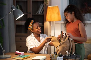 Mutlu, genç Afrikalı bir bayan, genç kızına yardım ediyor. Sabahları okul için sırt çantasıyla masada oturuyor.