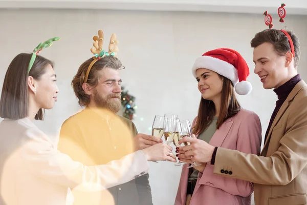シャンパンのフルーツでクリンクしているクリスマスのヘッドバンドの若いビジネスの人々は来年の成功した仕事のために乾杯します — ストック写真