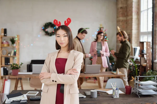 年轻的亚洲女商人穿着时髦的便服 头戴圣诞头饰 站在办公室里与一群同事进行讨论 — 图库照片