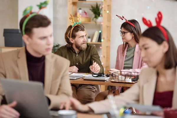 年轻自信的商人 戴着圣诞头巾 一边看着黑发女同事 一边帮她准备讲稿 — 图库照片