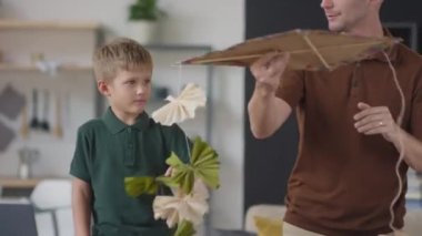 Belden yukarıda, mutlu baba ve oğulun renkli el yapımı uçan uçurtmayla oynarken eğlendiği ve birbirlerine beşlik çaktıkları el kamerası görüntüleri.