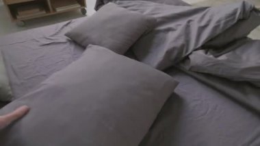 Kız arkadaşı arka planda oturma odasında egzersiz yaparken tanınmayan bir adamın sabah yatağını toplaması.