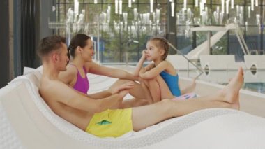 Kafkasyalı mutlu bir ailenin termal havuz kenarında dinlenirken, yüzme hareketlerini taklit ederken çekilmiş yavaş çekim görüntüleri.