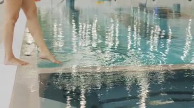 Düşük çözünürlüklü yavaş çekim görüntülerinde tanınmayan kadın, erkek ve küçük kız termal havuza kristal berrak suyla yaklaşıyorlar.